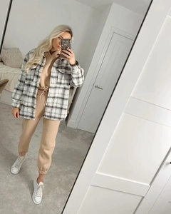 Détail d'une veste chemise à carreaux noir et blanc pour femme avec survêtement beige