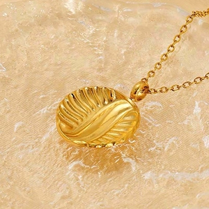 Macro shot of gold leaf-shaped pendant with embossed texture on an O-chain