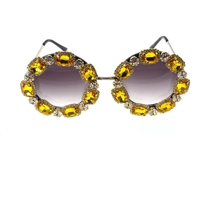 Detailed view of luxury oversized sunglasses with gold frames and purple gradient lenses