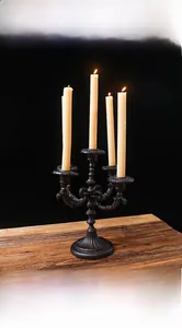 Close-up of vintage five-arm cast iron candelabra with cream candles on wood table