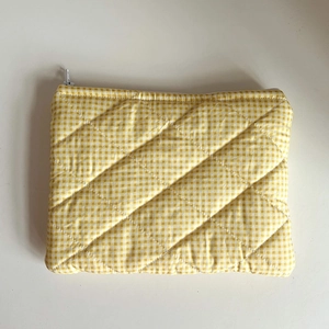 Detail view of yellow plaid quilted fabric and white metal zipper on cosmetic bag