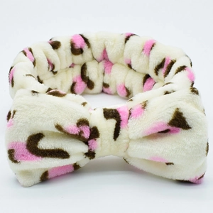 Beige plush leopard print headband with a pink bow for washing face and makeup