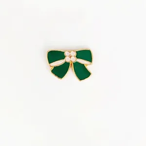 Close-up of a vintage dark green enamel bow brooch with gold-plated metal edges