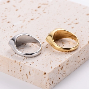 Minimalist gold and silver signet rings displayed on a textured beige travertine stone slab
