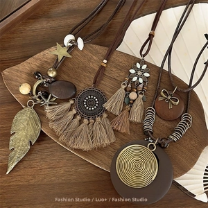 Bohemian retro layered long necklaces with tassels and metal charms on a wooden tray
