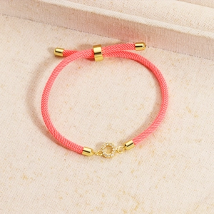 Detail of pink woven bracelet with gold slider clasp and crystal pavé ring charm