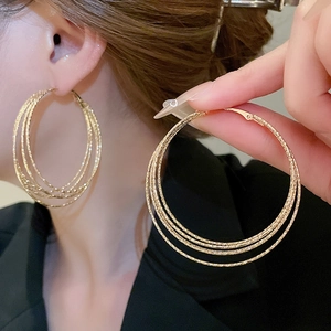 Elegant gold multi-layer textured hoop earrings worn by a model for a minimalist look