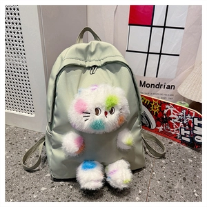 Dettaglio di uno zaino in nylon verde chiaro con una grande bambola di gatto in peluche colorata