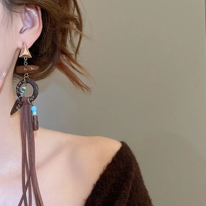 Close-up of Bohemian long tassel earrings with brown wood rings and blue bead details