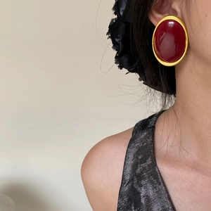 Close-up of model wearing retro oval red earrings with gold borders and resin texture
