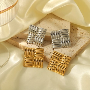 Makro-Detail der gesteppten Textur geometrischer Ohrringe in Gold- und Silberoptik