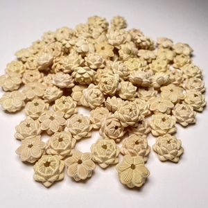Macro detail of hand-carved cream boxwood lotus flower beads with multi-layered petals