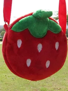 Cute strawberry shaped plush crossbody bag with green leaves and white embroidery on grass