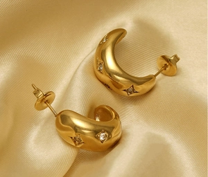 Macro detail of gold-plated chunky hoop earrings with sparkling inset star motifs
