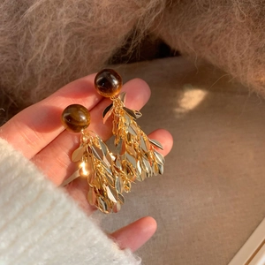 Close-up of vintage resin sphere earrings with golden leaf tassels and silver needle posts