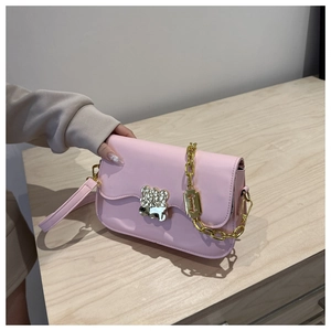 Gros plan détaillé d'un sac bandoulière en cuir rose avec un fermoir doré en forme d'ours