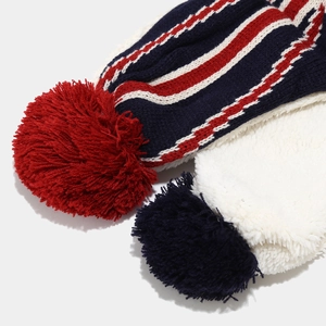 Close-up of thick knitted winter hats with faux fur pom-poms and striped Union Jack colors