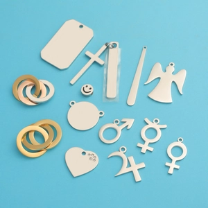 Polished stainless steel charms including heart, cross, and angel shapes on blue backdrop