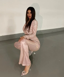Detail of sparkly pink long-sleeve jumpsuit showing the sequined fabric and draped fit