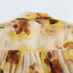 Detail der geblümten Schluppenbluse aus beige Chiffon mit gelb-braunem Muster