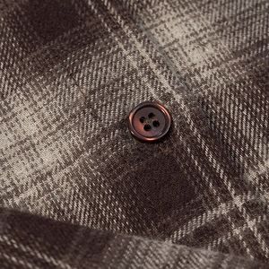 Détail d'une chemise à carreaux en flanelle avec bouton marron et texture du tissu