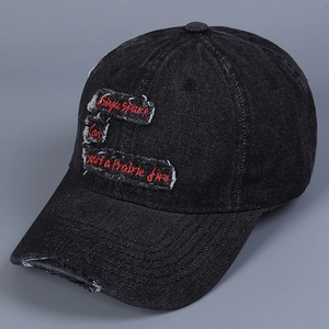 Close-up of distressed denim baseball cap with red embroidered text on black fabric