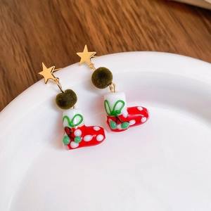 Detailed shot of Christmas tree earrings with green plush balls and red polka dot boots