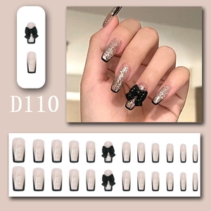 Detail of French nude press-on nails with black 3D bows and silver glitter gradient