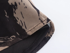 Close-up van mesh stof met bruin-zwarte print en gedetailleerde afwerking van naden