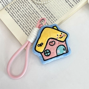 Detail of cartoon plush house charm with embroidery, pink carabiner and woven strap