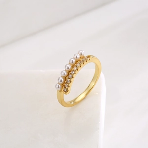 Détail d'une bague dorée double rangée avec perles blanches et zircons scintillants
