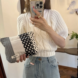 Handheld view of a large capacity black and white polka dot floral cosmetic pouch bag