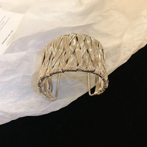 Macro detail of silver twisted wire mesh wide open bangle with woven metal texture