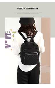 Close-up of black quilted nylon mini backpack featuring multiple zipper pockets and top handle