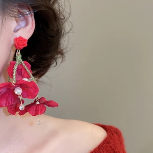 Detail of red fabric flower earrings with crystal tassels and pearls on model
