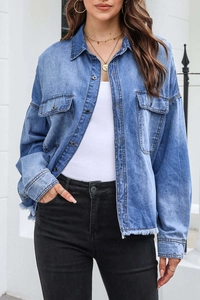 Detail of blue denim shirt with lapel collar, flap pockets and raw hem on a model