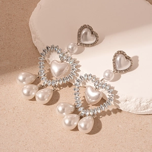 Elegant silver heart earrings with pearls and zircon crystals on a stone background