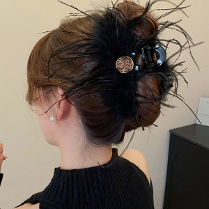 Détail de la pince à cheveux en plumes noires avec logo doré à motif léopard chic