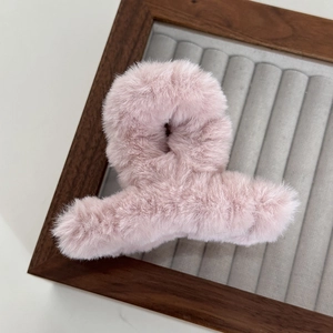 Close-up of soft pink plush hair claw clip displayed on a luxury grey velvet jewelry tray