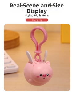 Close-up of pink flying pig bag charm with white wings and matching plastic carabiner hook