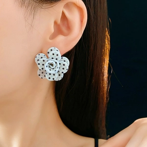 Gros plan sur des boucles d'oreilles fleurs bleues à pois noirs sur le mannequin