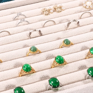 Grey velvet jewelry display tray showcasing emerald rings and pearl accessories