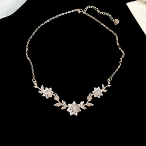 Macro detail of silver flower pendant necklace with cubic zirconia on black velvet