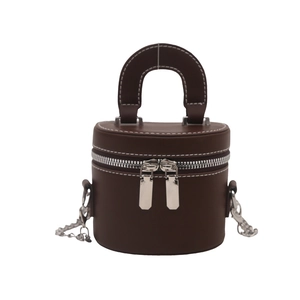Brown leather cylindrical vanity bag with white stitching and silver chain strap