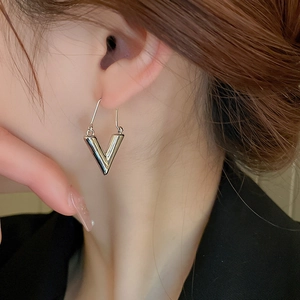 Gros plan d'une boucle d'oreille métallique argentée en forme de V au fini miroir poli