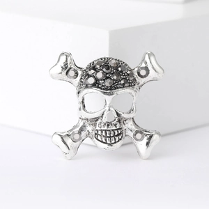 Silver punk skull and crossbones brooch with black rhinestones on a white background