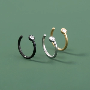 Detailed view of three C-shaped non-piercing nose rings in gold, silver, and black finish