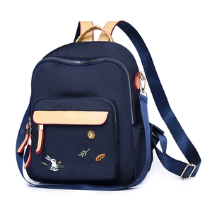 Zaino alla moda blu navy con cinturini beige e ricamo su sfondo bianco puro