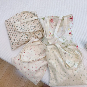Flat lay macro of four cotton tote bags featuring vintage floral prints on a white quilt