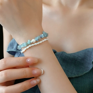 Gros plan d'un ensemble de bracelets avec éclats d'aigue-marine bleue et perles blanches